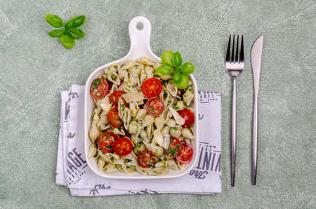 Shell pasta with tomatoes and pesto in a ceramic dish on a cement background. Selective focus.の写真素材