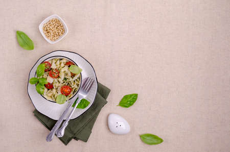 Shell pasta with tomatoes and pesto in a ceramic dish on a textile background. Selective focusの写真素材