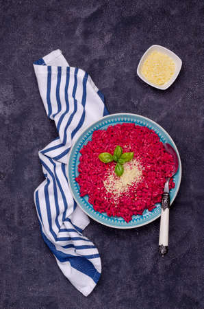 Beetroot risotto with cheese in a ceramic dish on a cement background. Top view. Selective focus.の写真素材