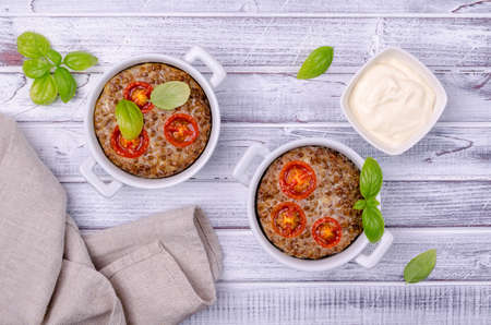 Buckwheat casserole with tomatoes and basil on a wooden background. Selective focus.の写真素材