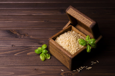 Dry orzo pasta in a dish on a wooden background. Top view. Selective focus.の写真素材