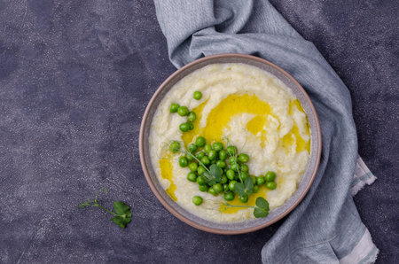 Vegetable cream soup with green peas and sprouts on a cement background. Selective focus.