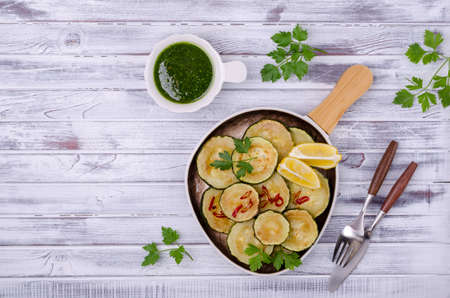 Fried zucchini with green sauce on a wooden background. Top view. Selective focus.の写真素材