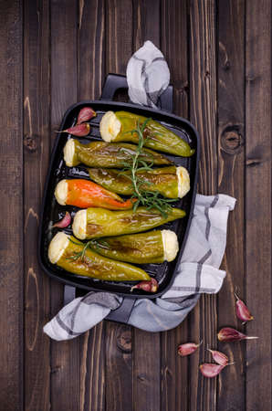 Baked green pepper stuffed with ricotta with garlic and rosemary on a wooden background. Top view. Selective focus.の写真素材