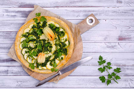 Round vegetable pie with green sauce on a wooden background. Top view. Selective focus.の写真素材