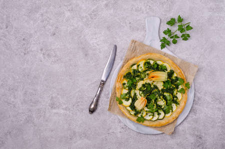 Round vegetable pie with green sauce on a concrete background. Top view. Selective focus.の写真素材