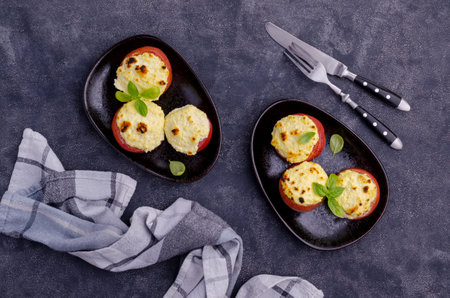 Stewed tomatoes stuffed with cheese on a stone background. Selective focus.の写真素材