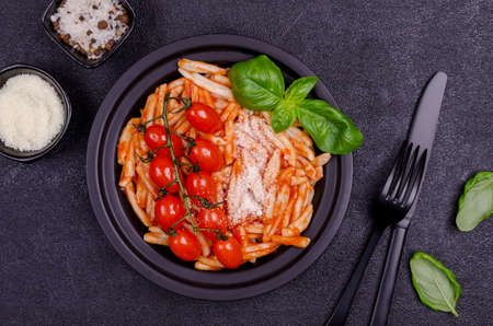 Pasta with tomatoes, red sauce and cheese on a black background. Selective focus. Top view.の写真素材