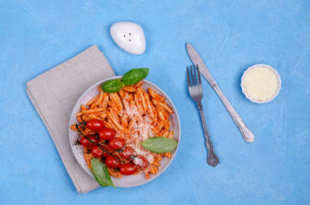 Pasta with tomatoes, red sauce and cheese on a blue background. Selective focus. Top view.の写真素材