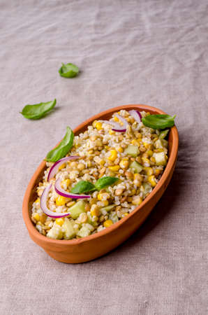 Lentil salad with wheat and vegetables in a ceramic dish on a textile background. Selective focus.の写真素材