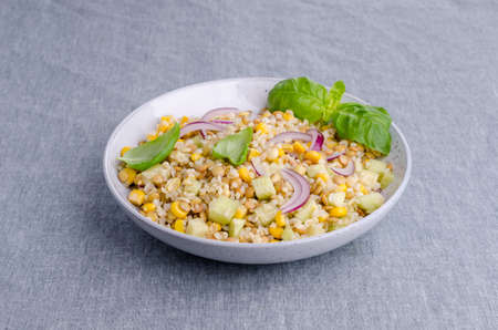 Lentil salad with wheat and vegetables in a ceramic dish on a textile background. Selective focus.の写真素材