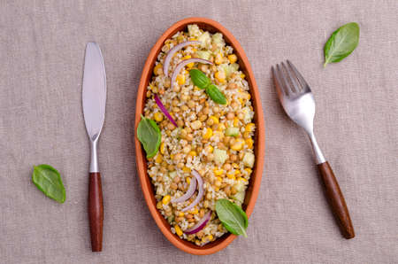 Lentil salad with wheat and vegetables in a ceramic dish on a textile background. Selective focus.の写真素材