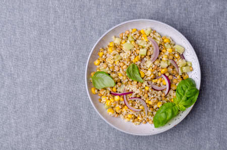 Lentil salad with wheat and vegetables in a ceramic dish on a textile background. Selective focus.の写真素材