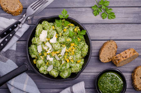 Gnocchi with corn and green sauce on a wooden background. Selective focus. Top view.の写真素材