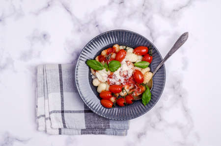 Gnocchi with tomatoes, red sauce, cheese and basil leaves on a marble background. Selective focus. Top view.の写真素材