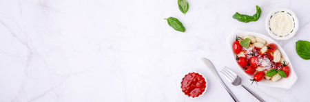 Gnocchi with tomatoes, red sauce, cheese and basil leaves on a marble background. Selective focus. Top view.の写真素材