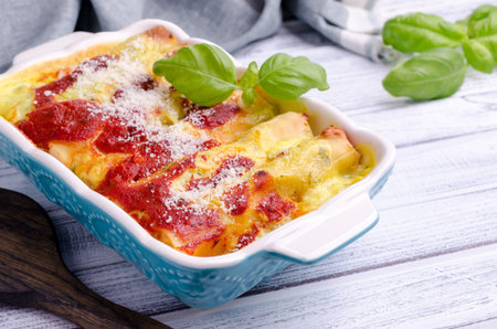 Traditional baked cannelloni with meat filling and sauce on a wooden background. Selective focus.