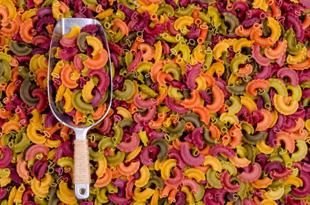 Multicolored dry pasta in a metal scoop. Background. Texture. design concept. Copy space.の写真素材