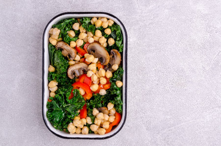 Fried vegetables with chickpeas in a ceramic plate on a stone background. Top view. Selective focus.の写真素材