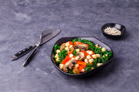 Fried vegetables with chickpeas in a ceramic plate on a stone background. Top view. Selective focus.の写真素材