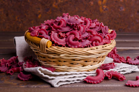 Dry traditional beetroot pasta. Wooden background. Top view.の写真素材