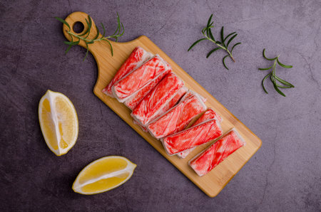 Crab meat sticks with lemon and rosemary. Top view. Selective focus.
