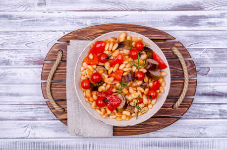 Braised beans with vegetables and fried sausages on a wooden background. Top view.の写真素材