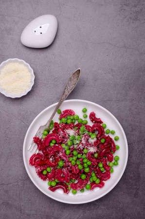 Beetroot pasta with green peas and cheese in a ceramic dish. selective focus.の写真素材