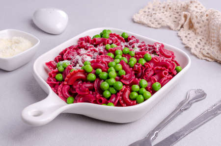Beetroot pasta with green peas and cheese in a ceramic dish. selective focus.の写真素材