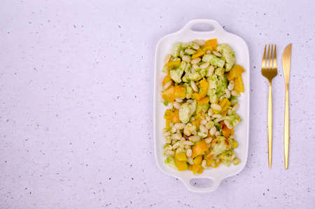 Vegetables with beans and green sauce in a ceramic dish on a slate background. selective focus. top view.の写真素材