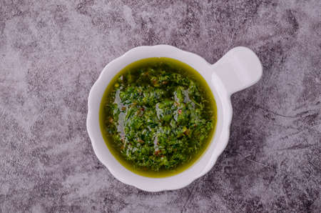 Green sauce in ceramic dishes on a gray stone background. selective focus. top view.の写真素材