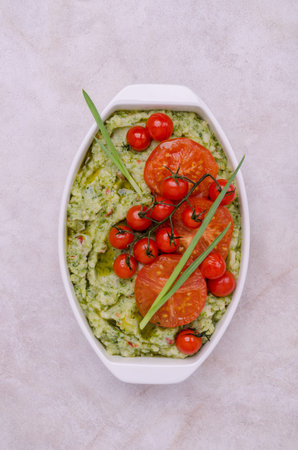 Spicy green mashed potatoes with fried tomatoes in a ceramic dish on a light background. top view.の写真素材