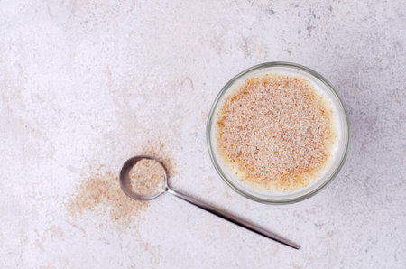 Brown psyllium with yogurt in glass on a stone background. top view.