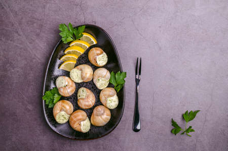 Traditional escargot with spicy butter in a ceramic dish with lemon and parsley. selective focus. top view.の写真素材