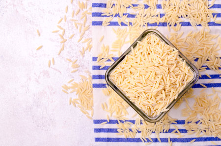 Dry risoni pasta in a glass jar on a light background. top view.の写真素材