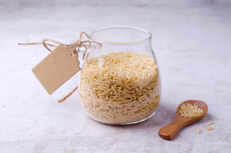 Dry risoni pasta in a glass jar on a light background. selective focus.の写真素材