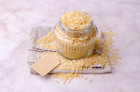 Dry risoni pasta in a glass jar on a light background. selective focus.の写真素材