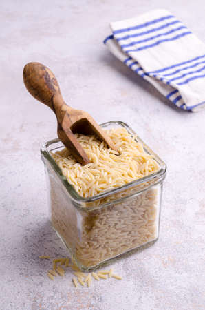 Dry risoni pasta in a glass jar on a light background. selective focus.の写真素材