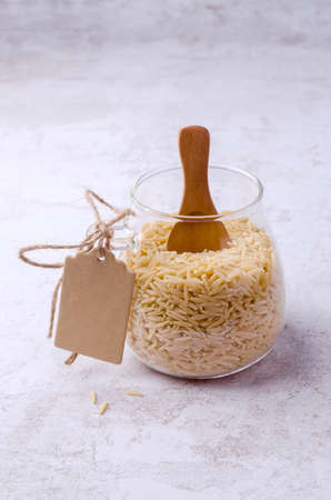 Dry risoni pasta in a glass jar on a light background. selective focus.の写真素材