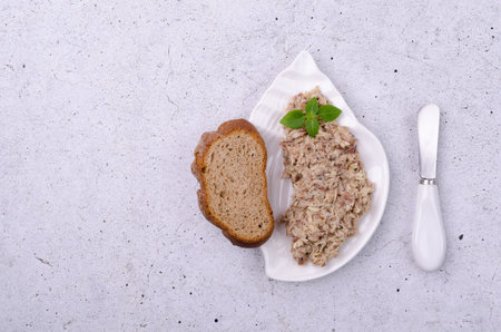 Fish pate with bread in a ceramic dish on a light background. top view.