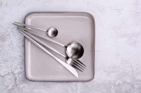 Clean silver metal cutleryon a gray cement background. design concept. top view.