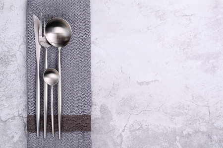 Clean silver metal cutleryon a gray cement background. design concept. top view.