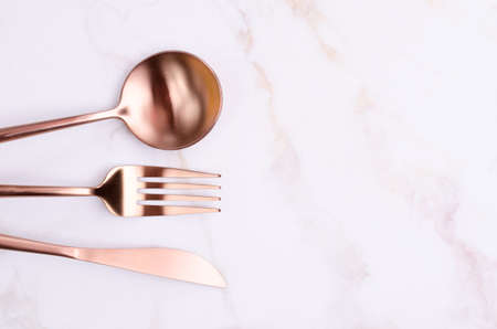 Clean golden metal cutleryon light marble background. design concept. top view.の写真素材