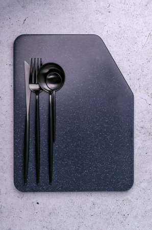 Clean black metal cutlery on a light gray background. design concept. top view.