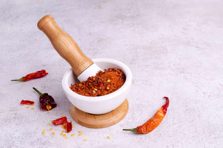 Red dry pepper powder and slices in a mortar on a light background. selective focus.の写真素材
