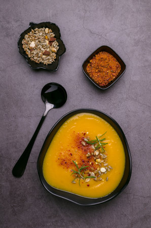 Yellow thick soup with nuts, seeds and red pepper on a dark background. top view.の写真素材