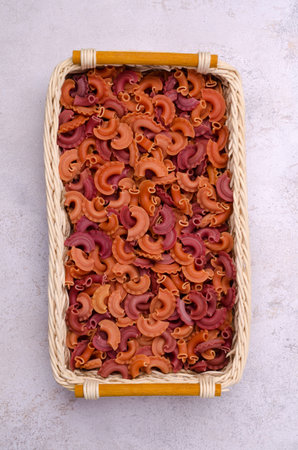 Dry red pasta in a wicker basket on a light background. design concept. top view. copyspace.