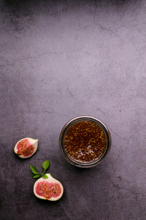 Jam figs in a glass jar on a dark background. top view. selective focus.の写真素材