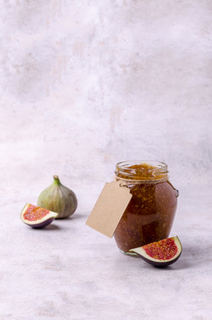 Jam figs in glass jar with a label on a light background. selective focus.の写真素材