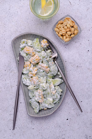 Raw vegetable salad with white sauce in a ceramic bowl on a light background. top view.の写真素材